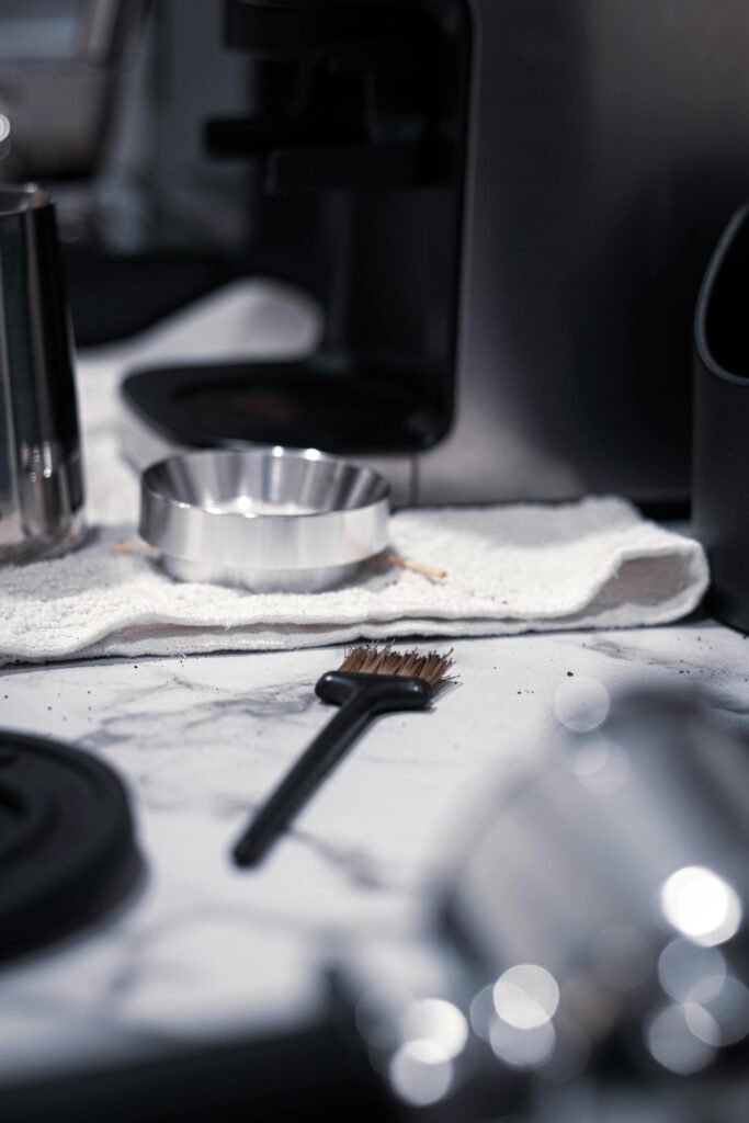 pexels photo 18272581 18272581 Detailed shot of coffee tools and brush on marble counter, with soft lighting.